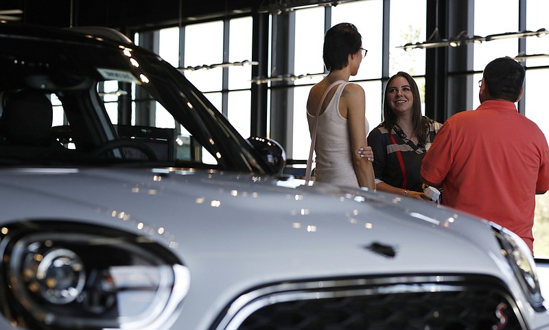 FILE - In this Aug. 30, 2018, file photo, a salesperson, center, confers with two customers interested in the 2018 Countryman on display in the showroom of a Mini dealership in Highlands Ranch, Colo. Choosing a smaller vehicle, leasing, or buying a used vehicle are a few of the recommended methods in lowering a car payment. (AP Photo/David Zalubowski, File)