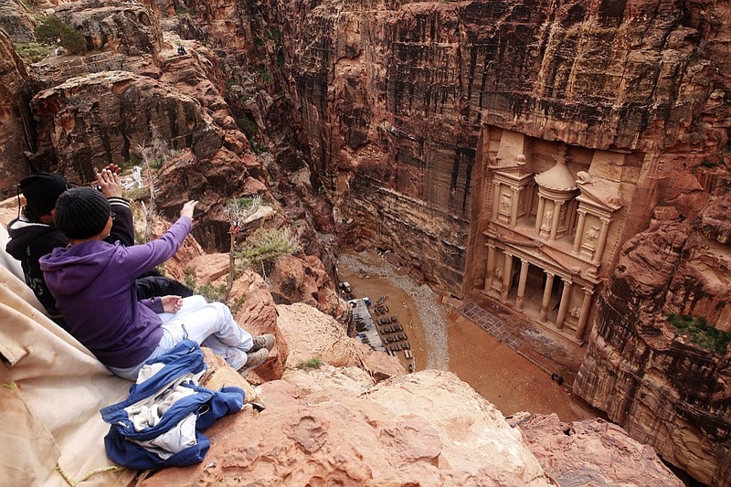 In this Feb. 13, 2017, file photo, tourists point at the Treasury, in the kingdom's Petra archaeological park, southern Jordan. A fictional caper about an antiquities heist set Petra has stirred widespread outrage over the film's portrayal of historical Jewish ties to Jordan, shining a light on the tenuous peace with neighboring Israel and prompting the government to suspend the movie's production. "Jaber" follows a Jordanian boy who uncovers a stone with a Hebrew inscription on it in the rose-colored, rock-hewn city of Petra. (AP Photo/Sam McNeil, File)