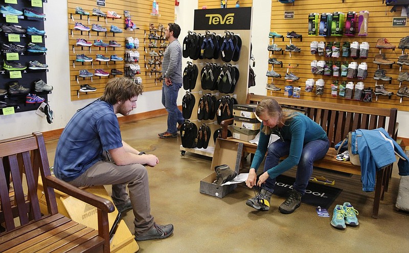 Liam Pinson, a sales associate, helps Melissa Stanley find hiking boots at Rock Creek Outfitters Friday, April 20, 2018, at 2 North Shore in Chattanooga.