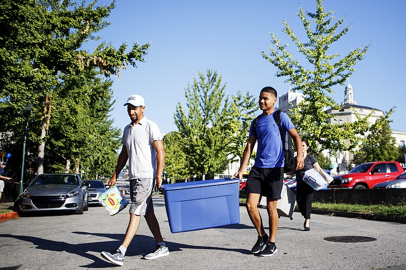 Staff photo by C.B. Schmelter/ Abram Moralez, right, and his father Rigoberto Moralez carry a box across 8th Street while moving in to his room on the campus of the University of Tennessee at Chattanooga on Thursday, Aug. 15, 2019 in Chattanooga, Tenn. Classes start on Monday, Aug. 19. Abram is a freshman from Memphis.
