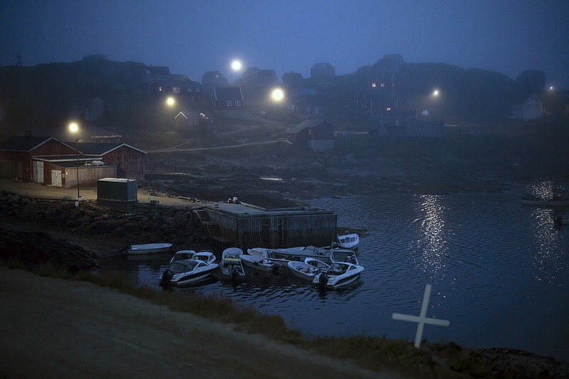 A cross sits on the side of the road as fog covers homes in Kulusuk, Greenland, early Thursday, Aug. 15, 2019. Greenland has been melting faster in the last decade and this summer, it has seen two of the biggest melts on record since 2012. (AP Photo/Felipe Dana)