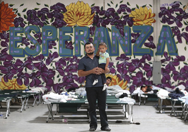 In this Wednesday, April 24, 2019 file photo, a Guatemalan man poses for a photo with his young son at the new Casa del Refugiado in east El Paso, Texas. Behind him is a full-wall mural which reads Esperanza, or hope. A federal appeals court ruling will allow the Trump administration to begin rejecting asylum at some parts of the U.S.- Mexico border for migrants who arrived after transiting through a third country. (Mark Lambie/The El Paso Times via AP, File)