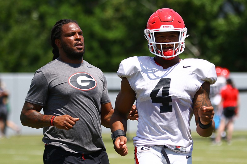 Georgia student assistant Jarvis Jones, a two-time All-American for the Bulldogs during the 2011-12 seasons, helps freshman outside linebacker Nolan Smith (4) during a drill earlier this month. / Georgia photo/Tony Walsh