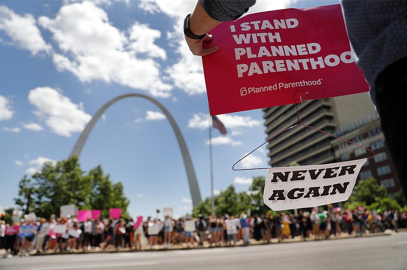 FILE - In this May 30, 2019, file photo, abortion-rights supporters stand on both sides of a street near the Gateway Arch as they take part in a protest in favor of reproductive rights in St. Louis. The Trump administration implemented a new rule for the federal family planning program known as Title X. Planned Parenthood, long a target of religious conservatives because of its role as the leading U.S. abortion provider, quit the program rather than comply with the new rule that prohibits clinics from referring women for abortions. (AP Photo/Jeff Roberson, File)