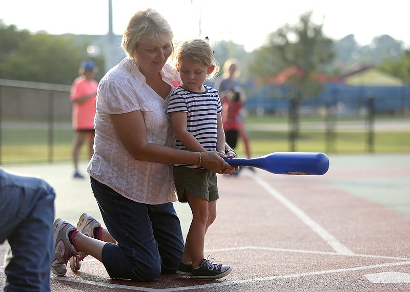 Staff photo by Erin O. Smith / Darlene Lentz, a vocational consultant with Siskin Hospital and board member with Chattanooga Area Brain Injury Association, helps Charlotte Jewell, 3, swing the bat during the Miracle League survivors vs. miracles ball game August 20, 2019 in Chattanooga, Tennessee. The Chattanooga Area Brain Injury Association board members and support group members participated in the event as well.