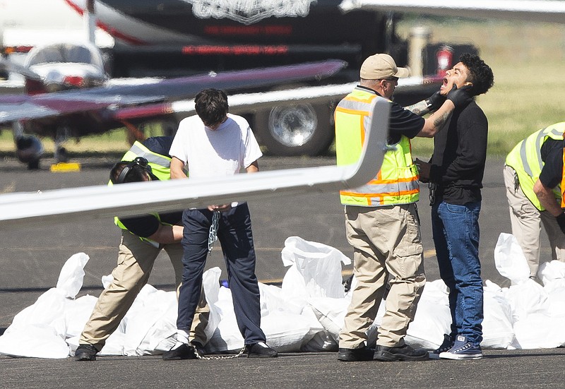 ICE detainees are searched before boarding a Swift Air flight on Tuesday, Aug. 20, 2019 at McCormick Air Center in Yakima, Wash. (Evan Abell/Yakima Herald-Republic via AP)