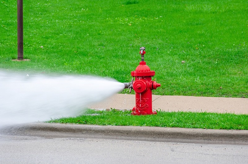 Bright red fire hydrant shooting out water at high pressure fire hydrant tile / Getty Images