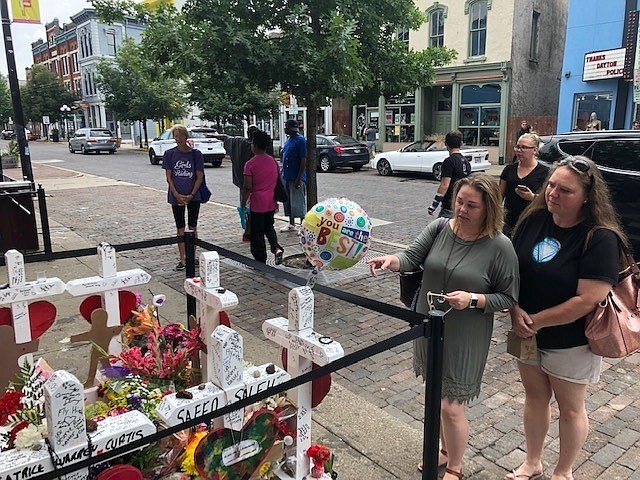 Sabrina Herman, gesturing, visits a makeshift memorial on Wednesday, Aug. 14, 2019, outside Ned Peppers nightclub in the Oregon District entertainment neighborhood where on Aug. 4 a gunman killed nine people, in Dayton Ohio. Herman, 41, of Dayton, a hospital social worker, visited with her sister, Tara Luikart, right, of Washington Court House. (AP Photo/Dan Sewell)