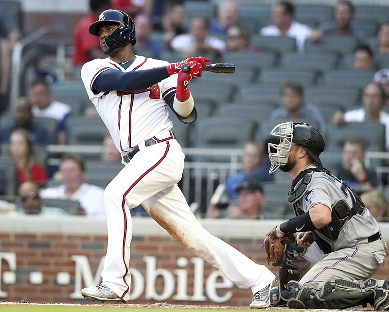 The Atlanta Braves' Adeiny Hechavarria, left, singles in a run as Miami Marlins catcher Bryan Holiday looks on during the second inning of Thursday night's game in Atlanta.