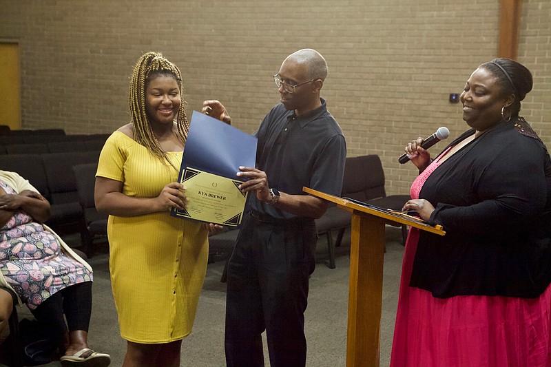 Kya Brewer accepts her diploma from the "Getting Ahead" program at Ochard Park Seventh-Day Adventist Church on August 22.