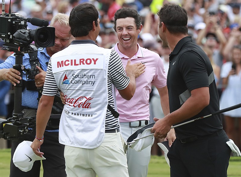 Rory McIlroy, center, celebrates with his caddy, Harry Diamond, left, with fellow PGA Tour golfer Brooks Koepka looking on after making his birdie putt to win the Tour Championship and The FedEx Cup on Sunday at East Lake Golf Club in Atlanta.