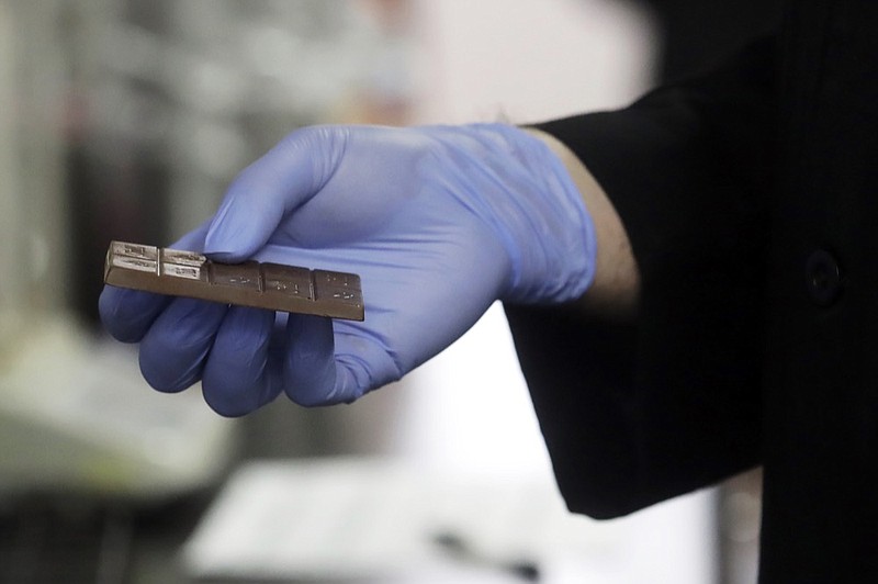 Chemist David Dawson holds a cannabis-infused chocolate bar as he demonstrates testing for THC and other chemicals at CW Analytical Laboratories in Oakland, Calif., Friday, Aug. 16, 2019. Chemists are trying to solve a scientific mystery involving marijuana brownies. Chocolate seems to throw off test results for potency. That could be dangerous for consumers looking to relax, not hallucinate. (AP Photo/Jeff Chiu)