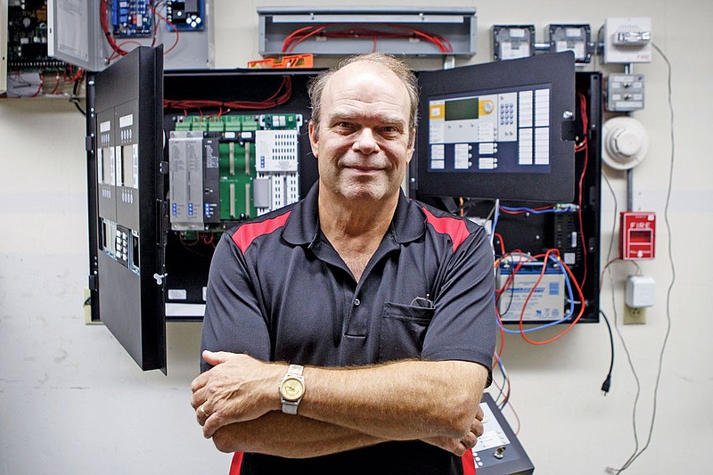 CEO and Managing Owner Gaines Campbell poses with examples of open fire alarm panels at the offices of IEC Fire, Security and Time.