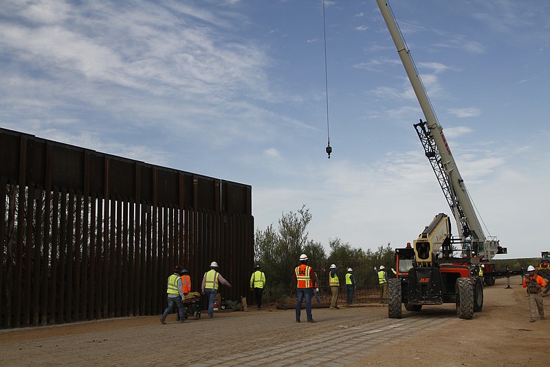 Workers break ground recently on new border wall construction about 20 miles west of Santa Teresa, New Mexico. The wall visible on the left was built in 2018 with money allocated by Congress, while the new construction is funded by money reallocated from Department of Defense funding. (AP Photo/Cedar Attanasio)