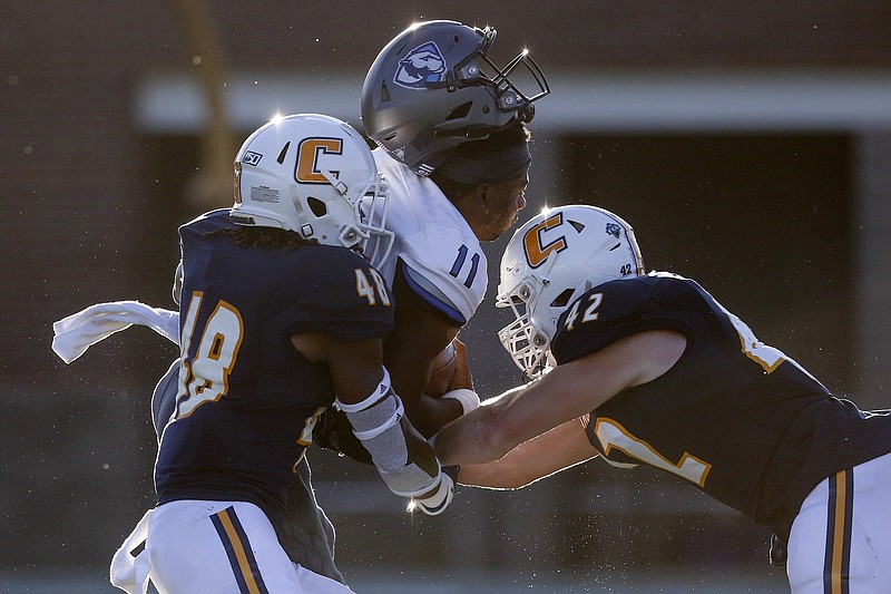Staff photo by C.B. Schmelter / Eastern Illinois quarterback Johnathan Brantley (11) loses his helmet as he is hit by University of Tennessee at Chattanooga linebackers C.J. Winston (48) and Marshall Cooper (42) at Finley Stadium on Thursday, Aug. 29, 2019 in Chattanooga, Tenn.