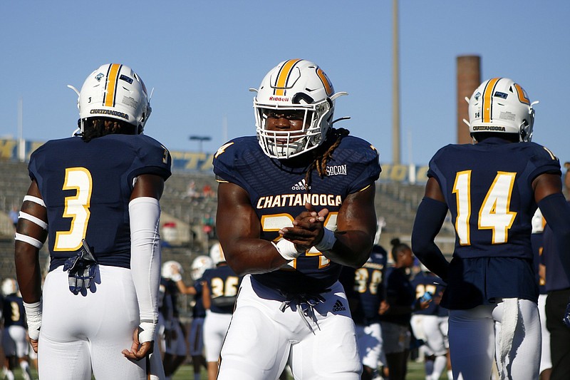 Staff photo by C.B. Schmelter / UTC running back Elijah Ibitokun-Hanks, center, greets his teammates as they take the field to warm up for their 2019 season opener against Eastern Illinois on Aug. 29 at Finley Stadium.
