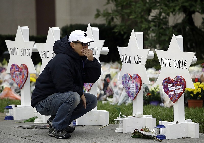 FILE - In this Oct. 29, 2018, file photo, a person pauses in front of Stars of David with the names of those killed in a deadly shooting at the Tree of Life Synagogue, in Pittsburgh. The two mass shootings and a presidential tweet put a spotlight on the idea of “domestic terrorism,” adding momentum to a debate about whether such attacks should be classified and tried in the same way as crimes against America by foreign terrorist groups and their supporters. (AP Photo/Matt Rourke, File)