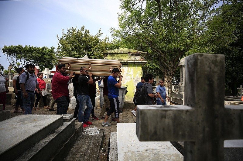 Mourners carry the coffin that contain the remains of Erick Hernandez Enriquez, also known as DJ Bengala, who was killed in an attack on the White Horse nightclub where he was DJ'ing, as they bring him for burial at the municipal cemetery in Coatzacoalcos, Veracruz state, Mexico, Thursday, Aug. 29, 2019. At least seven of the more than two dozen victims were laid to rest in the municipal cemetery Thursday afternoon, in overlapping burials two days after gang members blocked the club's exits and set it on fire. (AP Photo/Rebecca Blackwell)