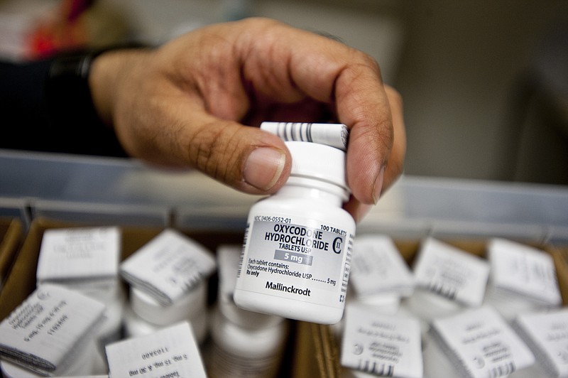 New York Times file photo — A pharmacist holds a bottle of oxycodone.