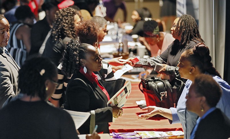 FILE - In this Aug. 14, 2019, file photo company representatives from Verizon, Goodwill, Kaiser Permanente and UPS, right, talk with potential applicants during a job and resource fair in Atlanta. On Friday, Sept. 6, the U.S. government issues the August jobs report. (Bob Andres/Atlanta Journal-Constitution via AP, File)