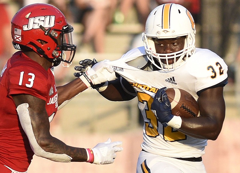 Staff Photo by Robin Rudd / UTC running back Ailym Ford (32) fights to break the tackle of Jacksonville State's Traco Williams during Saturday night's game in Jacksonville, Ala.