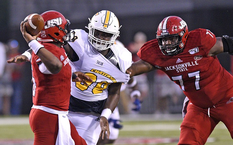 Staff Photo by Robin Rudd / UTC's Christian Smith pressures Jacksonville State quarterback Zerrick Cooper as Deandre Butler tries to protect the passer during Saturday night's game in Jacksonville, Ala.