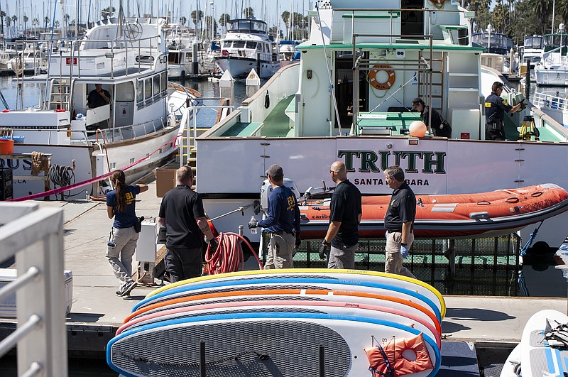 Authorities walk outside the Truth, a Truth Aquatics-owned dive boat, docked in the Santa Barbara Harbor in Santa Barbara, Calif., Sunday, Sept. 8, 2019. Authorities served search warrants Sunday at the Southern California company that owned the scuba diving boat that caught fire and killed 34 people last week. (AP Photo/ Christian Monterrosa)