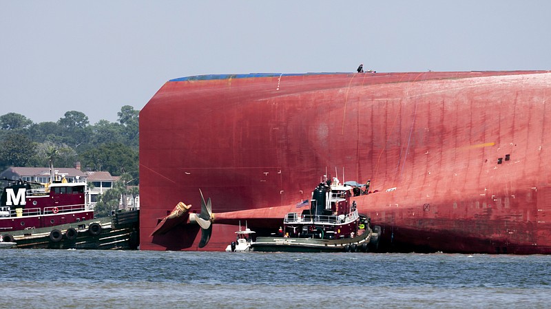 Rescuers work near the stern of the vessel Golden Ray as it lays on its side near the Moran tug boat Dorothy Moran, Monday, Sept. 9, 2019, in Jekyll Island, Ga. Coast Guard rescuers have made contact with four South Korean crew members trapped inside the massive cargo ship off the coast of Georgia. (AP Photo/Stephen B. Morton)