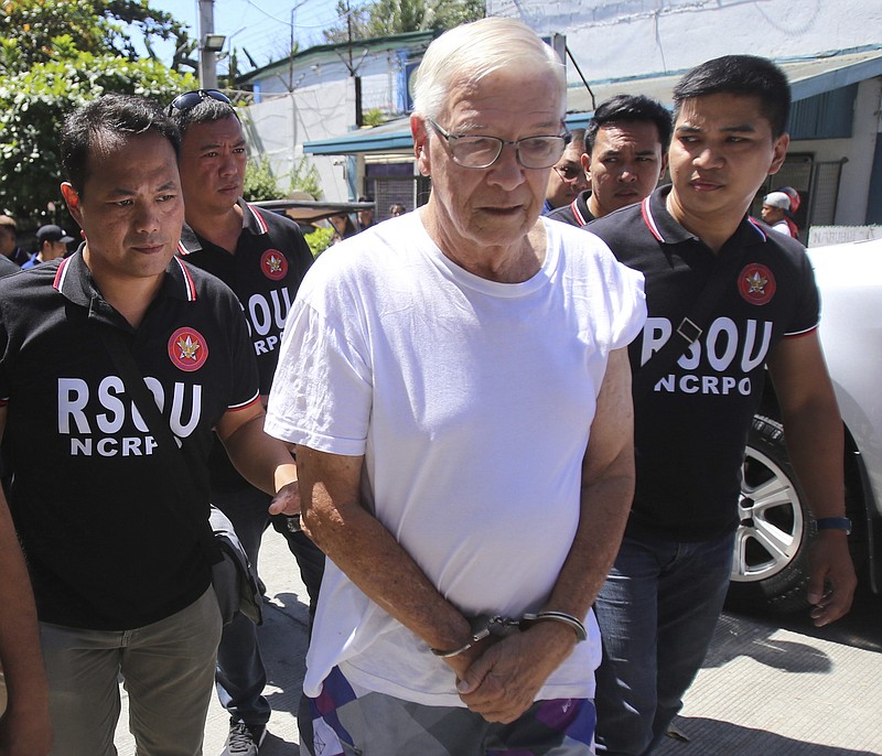 In this Feb. 19, 2019 photo, Philippine National Police, National Capital Region Police Office (NCRPO) agents escort Catholic priest Father Pius Hendricks to be served five additional arrest warrants at the Regional Special Operations Unit at Camp Bagong Diwa in suburban Taguig, east of Manila, Philippines. Investigators say about 20 boys and men, one as young as 7, have accused the priest of sexual abuse at his parish in Talustosan village, Naval township, Biliran province in central Philippines. (AP Photo)
