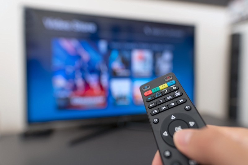 Multimedia streaming concept. Hand holding remote control. Video on demand tv tile advertising commercial / Getty Images
