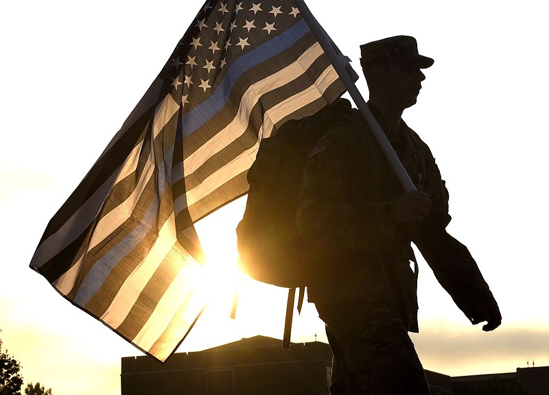 Staff Photo by Robin Rudd/ A UTC ROTC Cadet carries at the American Flag recalling police officers lost in 911 past the rising sun. From 6 a.m. until 5:00, on September 11, 2019 the American Flag, carried by members of the Military Science Department at the University of Tennessee at Chattanooga, students and staff, continuously circled Chamberlain Field on the University's campus in commemoration of 9/11.