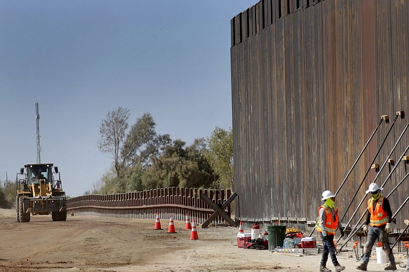 Government contractors erect a section of Pentagon-funded border wall along the Colorado River, Tuesday, Sept. 10, 2019 in Yuma, Ariz. The 30-foot high wall replaces a five-mile section of Normandy barrier and post-n-beam fencing, shown at left, along the the International border that separates Mexico and the United States. Construction began as federal officials revealed a list of Defense Department projects to be cut to pay for President Donald Trump's wall. (AP Photo/Matt York)