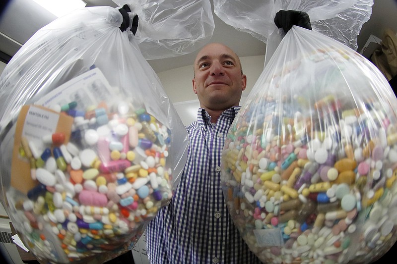 Narcotics detective Ben Hill, with the Barberton Police Department, shows two bags of medications that are are stored in their headquarters and slated for destruction, Wednesday, Sept. 11, 2019, in Barberton, Ohio. Attorneys representing some 2,000 local governments said Wednesday they have agreed to a tentative settlement with OxyContin maker Purdue Pharma over the toll of the nation's opioid crisis. (AP Photo/Keith Srakocic)