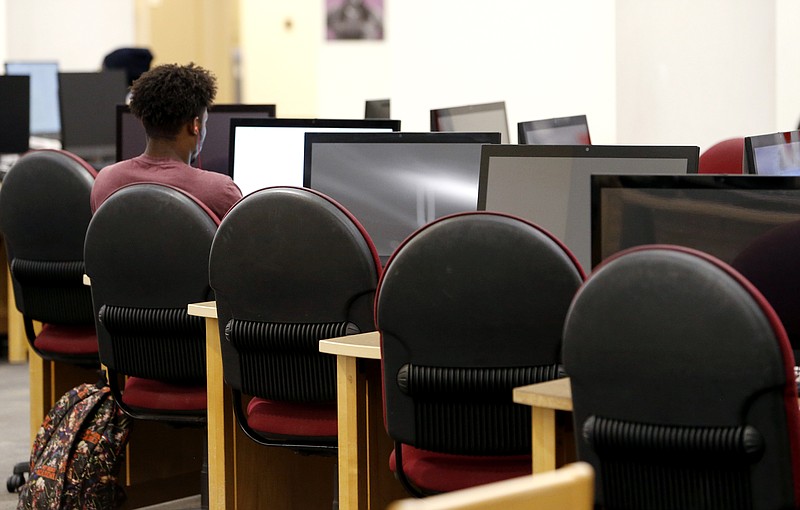 In this June 20, 2019, photo a Virginia Commonwealth University student works at a library workstation at the school in Richmond, Va. Students and their families can begin to submit two key applications for financial aid on Oct. 1 to help pay for higher education for the following school year. And filing early has its perks: better access to limited funds and a quicker response from schools on aid packages. (AP Photo/Steve Helber)