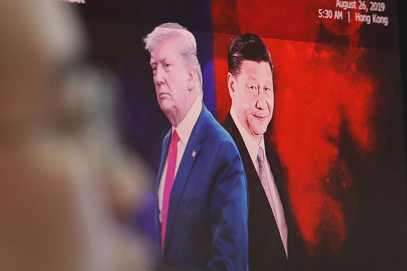 FIEL - In this Aug. 26, 2019, file photo, a computer screen shows images of Chinese President Xi Jinping, right, and U.S. President Donald Trump as a currency trader works at the foreign exchange dealing room of the KEB Hana Bank headquarters in Seoul, South Korea. China will lift punitive tariffs imposed on U.S. soybeans and pork in a trade war with Washington, a state news agency said Friday, Sept. 13, 2019, in a possible goodwill gesture ahead of negotiations. (AP Photo/Ahn Young-joon, File)