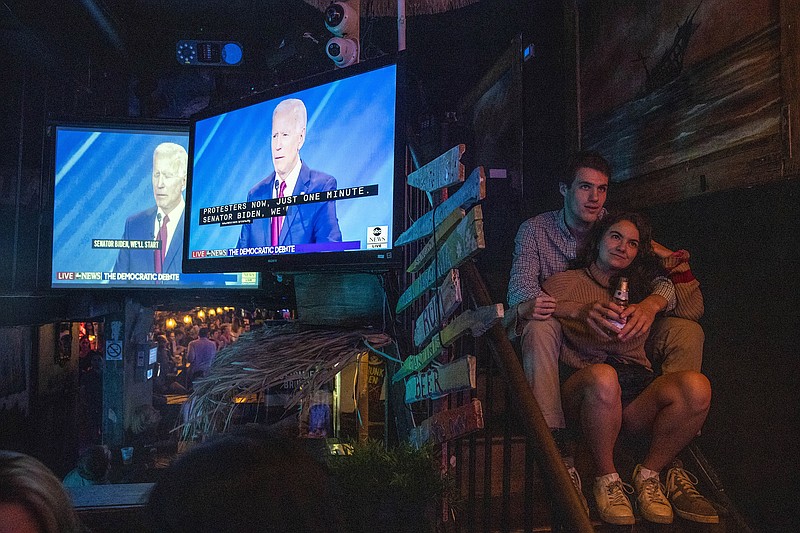 Photo by Brittainy Newman of The New York Times/Sam Sugerman and Naomi Bennett watch former Vice President Joe Biden during the televised Democratic presidential debate at Wicked Willy's in New York, on Thursday, Sept. 12, 2019.