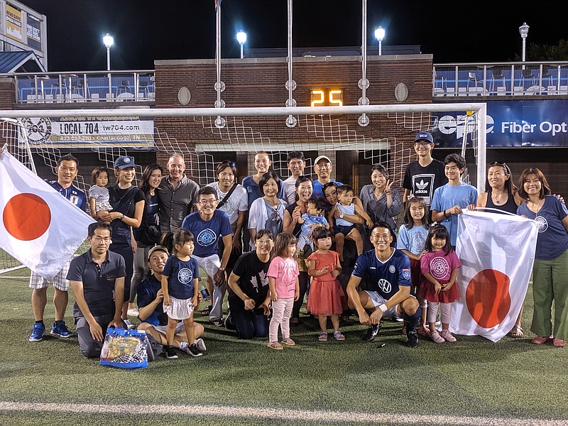 CFC photo by Sheldon Grizzle / CFC player Genki Miyachi, near bottom right, poses for a picture with his fan club after a home match this season.