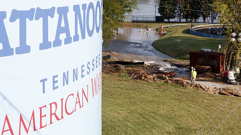 Staff photo by C.B. Schmelter / Workers are seen as water floods by a Tennessee American Water alongside the Tennessee River on Friday. A break in a major 36-inch line left much of Chattanooga without water for more than a day.