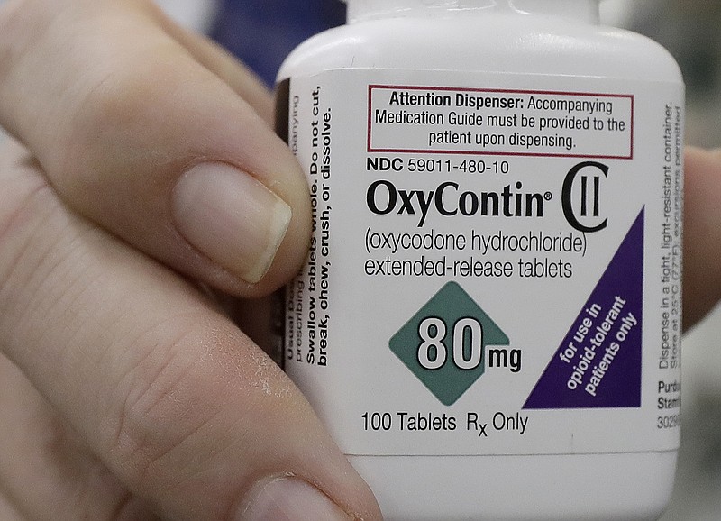 In this April 2, 2018, file photo, a pharmacist in San Francisco poses for photos holding a bottle of OxyContin. In court papers filed in New York on Sunday, Sept. 15, 2019, Purdue Pharma, the drug's manufacturer, flied for Chapter 11 bankruptcy protection. (AP Photo/Jeff Chiu, File)