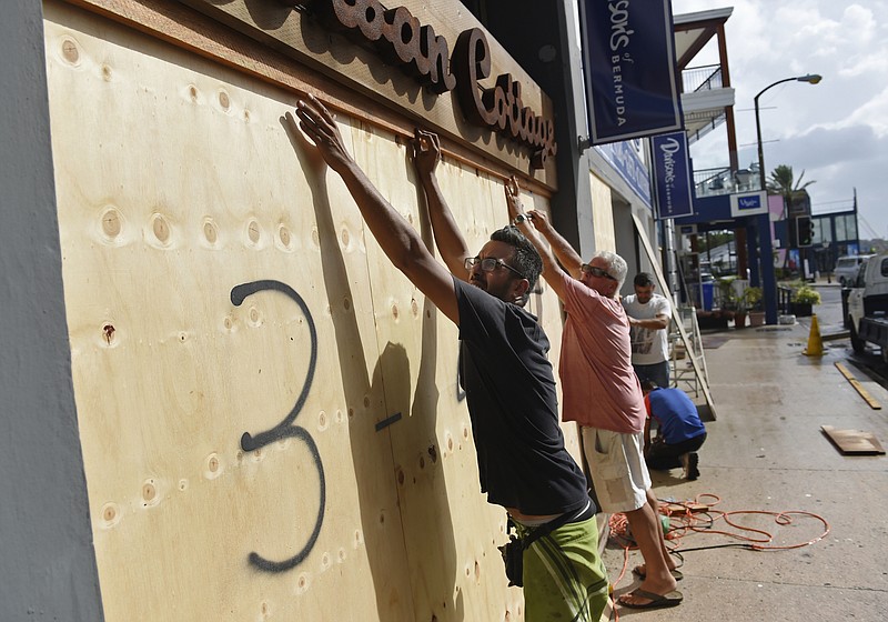 People board up an Urban Cottage store in preparation for Hurricane Humberto in Hamilton, Bermuda, Wednesday, Sept. 18, 2019. Bermuda's government called up troops and urged people on the British Atlantic island to make final preparations for an expected close brush Wednesday with Hurricane Humberto, a powerful Category 3 storm. Authorities ordered early closings of schools, transportation and government offices. (AP Photo/Akil J. Simmons)