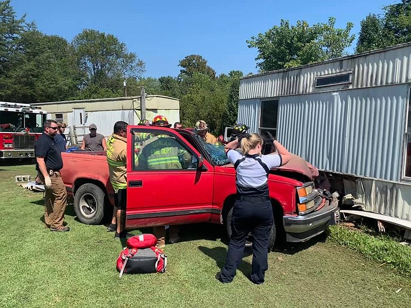 Photo courtesy of Sequatchie County EMA-911 director Winfred Smith / Dunlap firefighters on Monday work to extricate a driver whose vehicle collided with two mobile homes on Cross Street.
