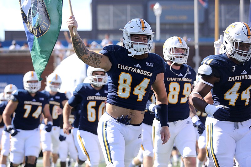 Staff photo by Erin O. Smith / UTC's Gage Upshaw (84) carries a flag as the Mocs run onto the field before Saturday's game against James Madison University at Finley Stadium.