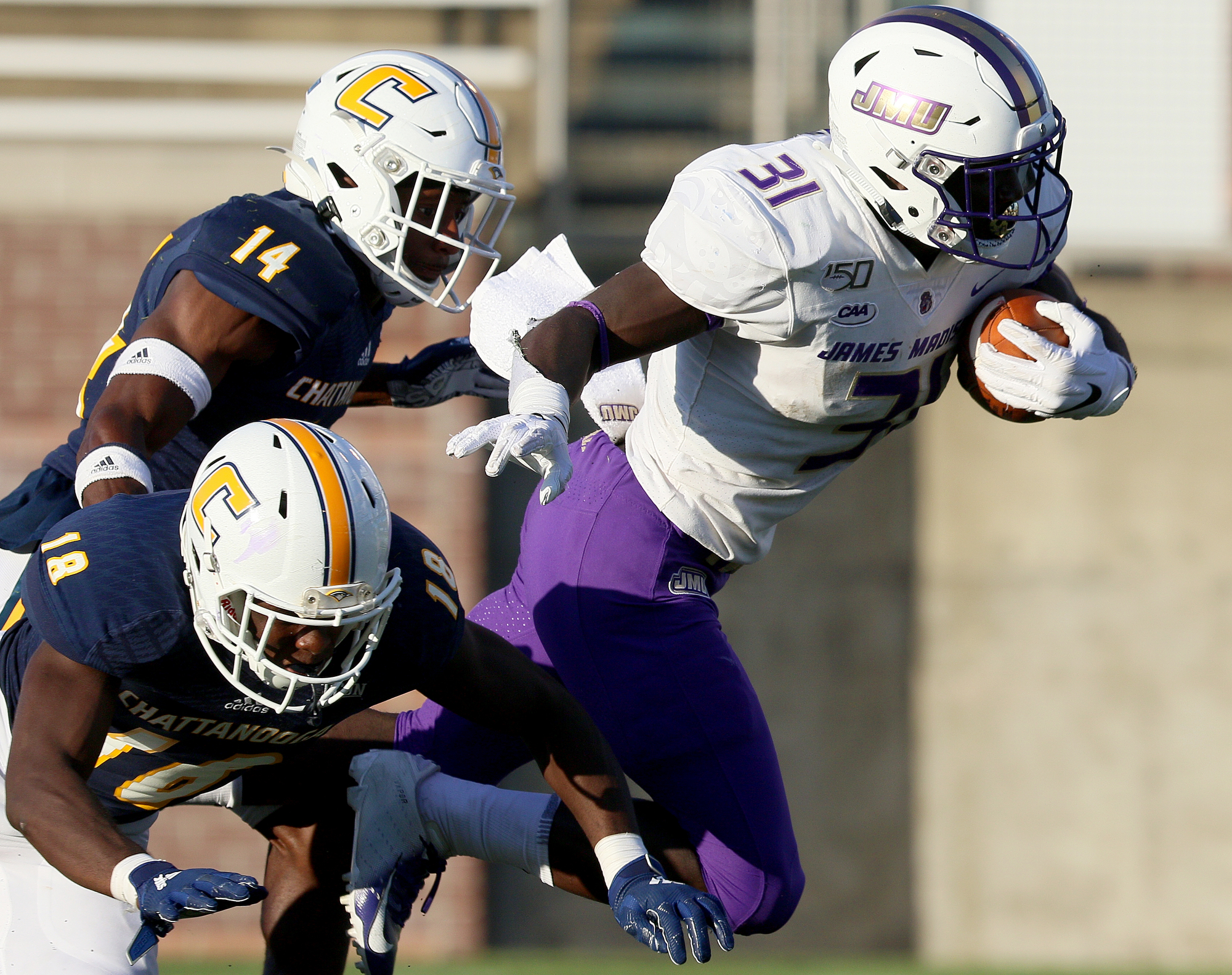 Staff photo by Erin O. Smith / James Madison University's Percy Agyei-Obese (31) is tripped up by UTC's Aaron Floyd (18) and Jordan Jones (14) during the UTC vs. James Madison University NCAA football game Saturday, August 21, 2019 at Finley Stadium in Chattanooga, Tennessee. JMU beat UTC with a score of 37-14.
