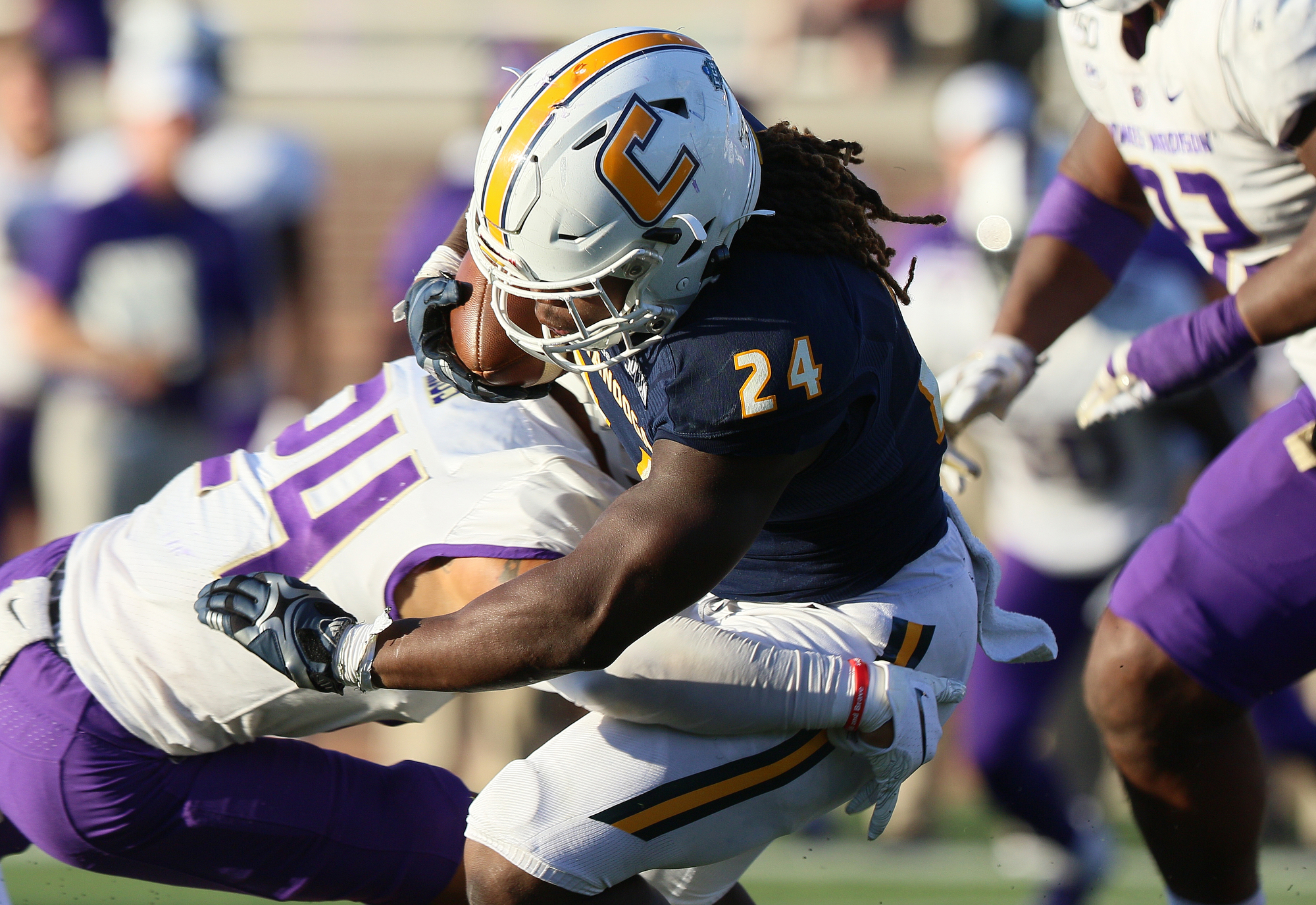 Staff photo by Erin O. Smith / UTC's Elijah Ibitokun-Hanks (24) is tackled by James Madison University's D'Angelo Amos (24), on left, as Ibitokun-Hanks runs the ball during the UTC vs. James Madison University NCAA football game Saturday, August 21, 2019 at Finley Stadium in Chattanooga, Tennessee. JMU beat UTC with a score of 37-14.