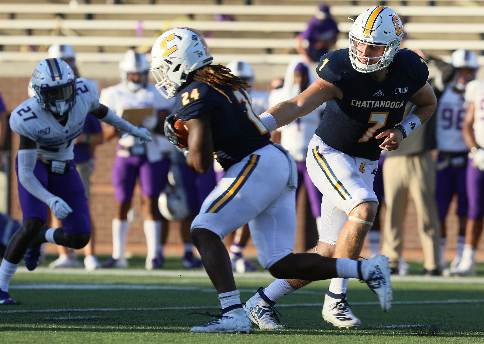 Staff photo by Erin O. Smith / UTC's Elijah Ibitokum-Hanks (24) takes the handoff from quarterback Nick Tiano (7) during the UTC vs. James Madison University NCAA football game Saturday, August 21, 2019 at Finley Stadium in Chattanooga, Tennessee. JMU beat UTC with a score of 37-14.