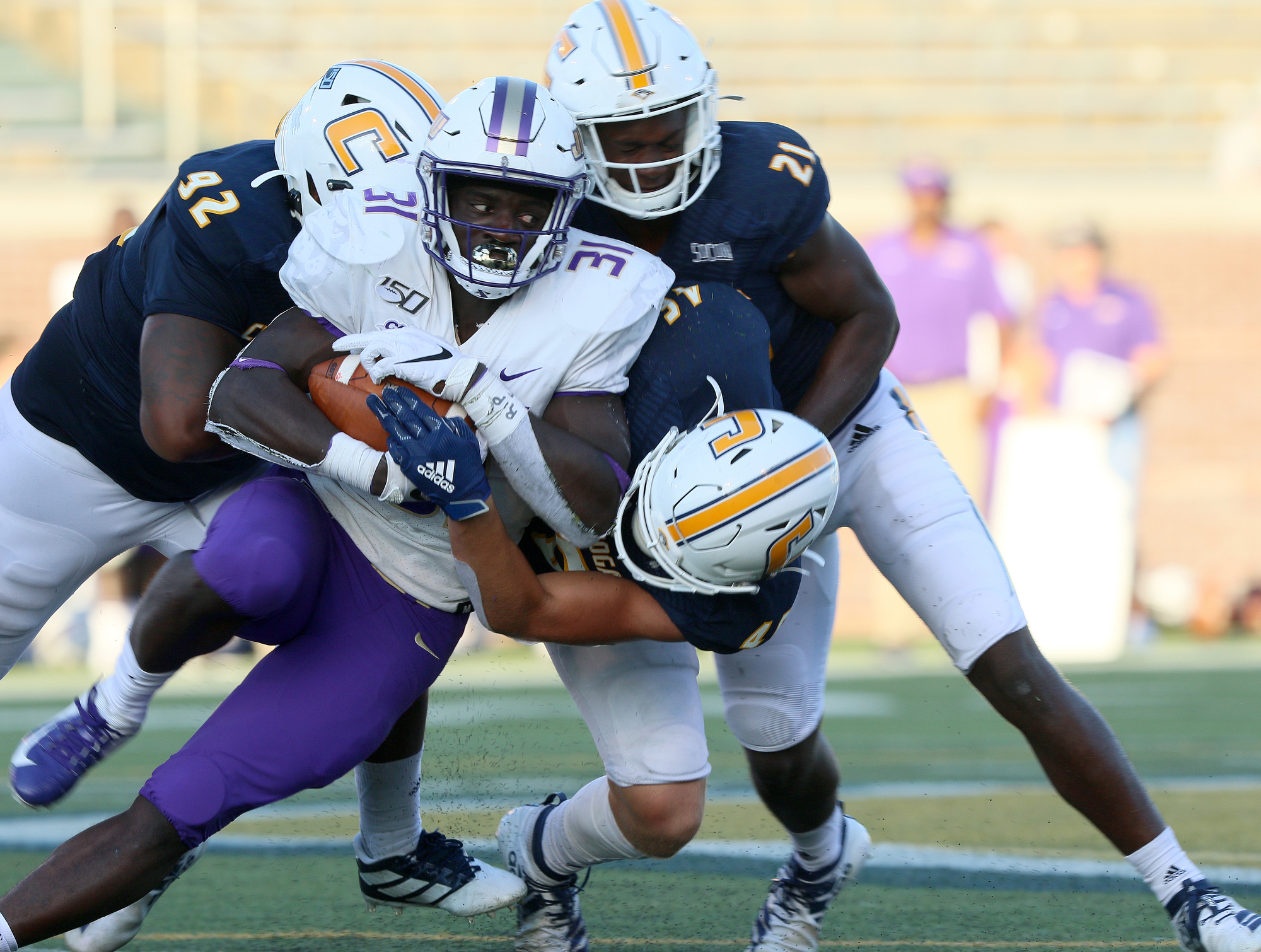 Staff photo by Erin O. Smith / James Madison University's Percy Agyei-Obese (31) is tackled by UTC's Telvin Jones (92), Ty Boeck (46) and D.J. Jackson (21) during the UTC vs. James Madison University NCAA football game Saturday, August 21, 2019 at Finley Stadium in Chattanooga, Tennessee. JMU beat UTC with a score of 37-14.