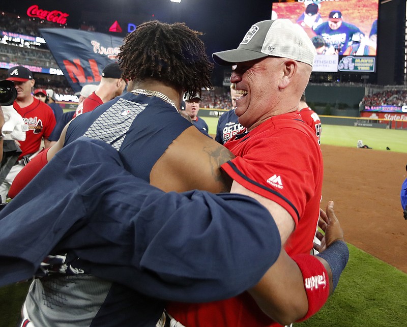 Associated Press photo by John Bazemore / Atlanta Braves manager Brian Snitker, right, hugs Ronald Acuña Jr. after the team beat the San Francisco Giants on Friday to clinch the NL East title.