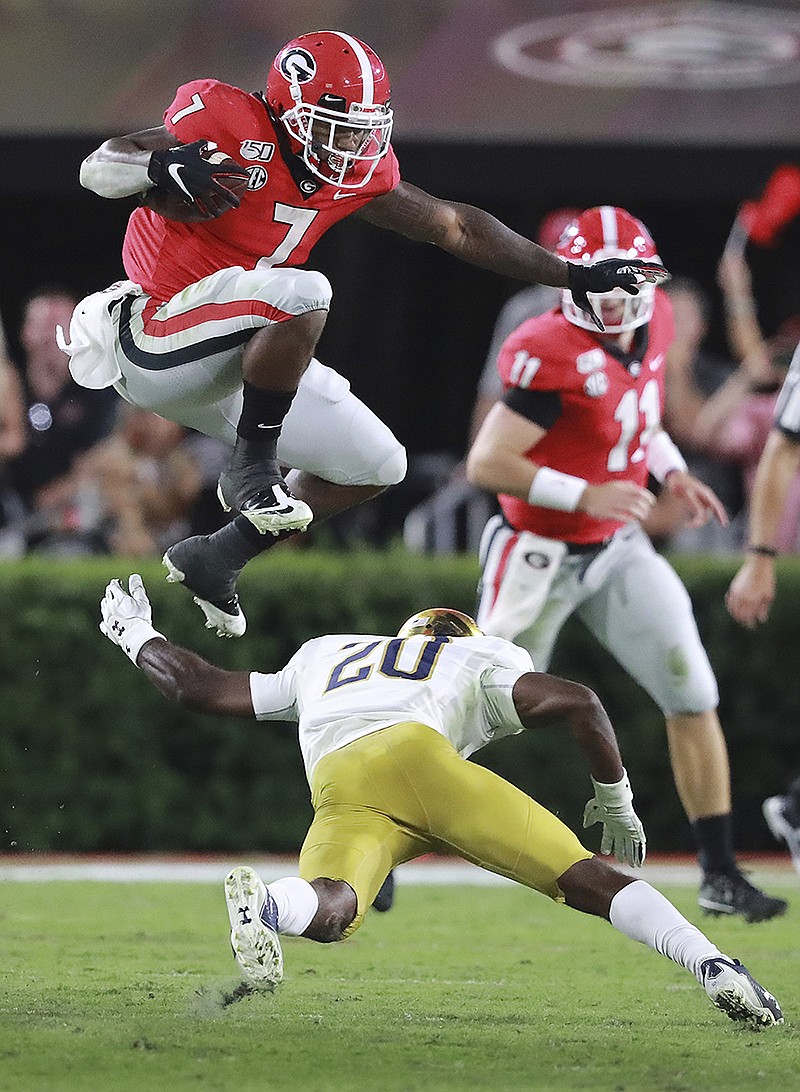 Associated Press photo by Curtis Compton / Georgia tailback D'Andre Swift leaps over Notre Dame cornerback Shaun Crawford to pick up a first down with quarterback Jake Fromm watching during the third quarter of Saturday night's game at Sanford Stadium in Athens, Ga.