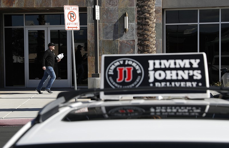 FILE - In this Feb. 6, 2019, photo, Tyler Schwecke, a delivery driver for Jimmy John's, makes a delivery in Las Vegas. The parent company of Arby’s and Buffalo Wild Wings is buying Jimmy John’s Sandwiches. (AP Photo/John Locher, File)