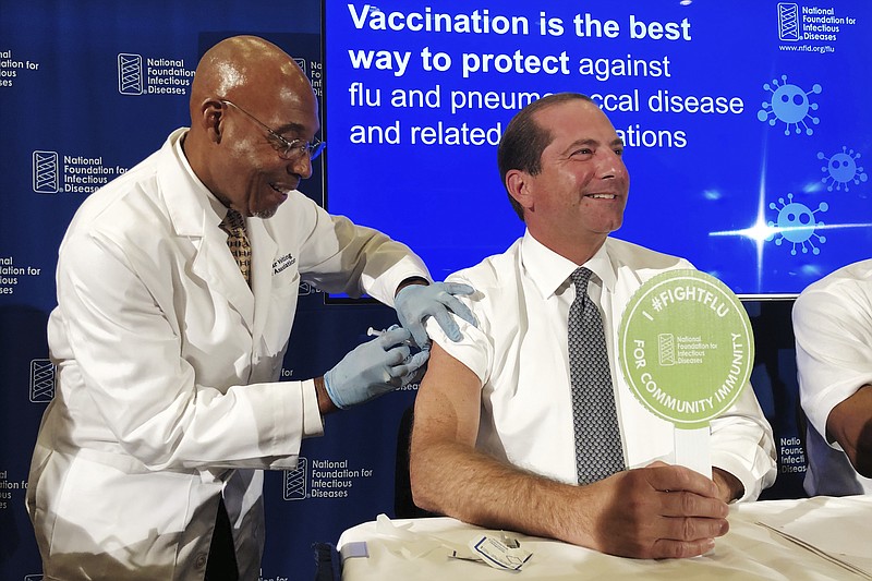 B.K. Morris, a nurse with MedStar Visiting Nurses Association, gives a flu shot to Secretary of Health and Human Services Alex Azar during a news conference in Washington. The flu forecast is cloudy and it's too soon to know if the U.S. is in for a third miserable season in a row, but health officials said Thursday, Sept. 26, 2019, not to delay vaccination. (AP Photo/Lauran Neergaard)